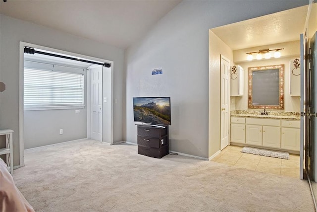 carpeted bedroom featuring ensuite bath, vaulted ceiling, and sink