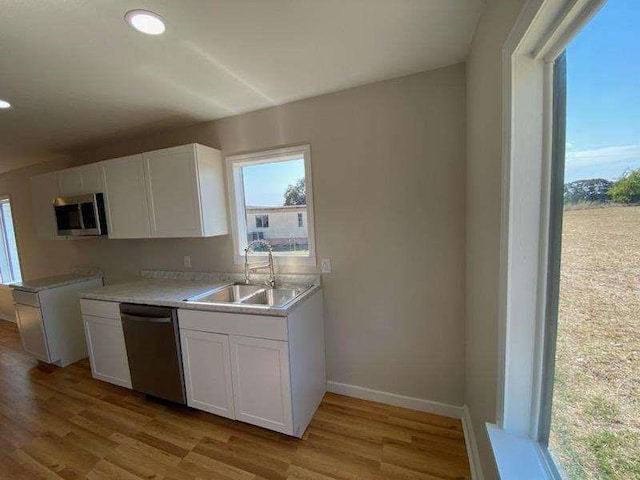 kitchen with white cabinets, appliances with stainless steel finishes, light hardwood / wood-style flooring, and sink