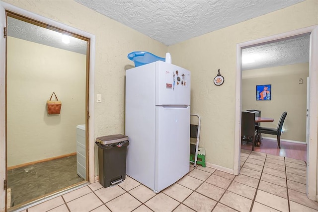 kitchen featuring white fridge, light tile patterned floors, and a textured ceiling