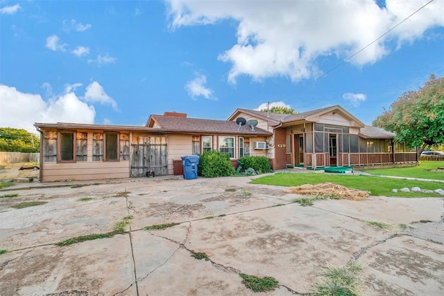 rear view of house featuring a lawn and a sunroom