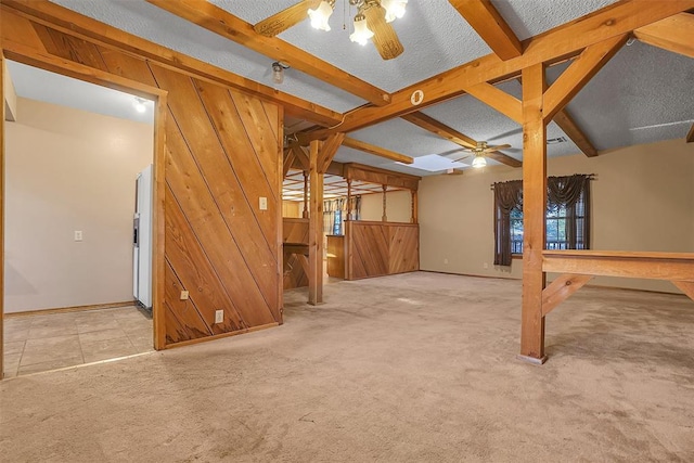 basement featuring light carpet, a textured ceiling, ceiling fan, and wood walls