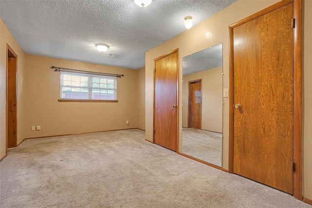 unfurnished bedroom with light carpet, a closet, and a textured ceiling