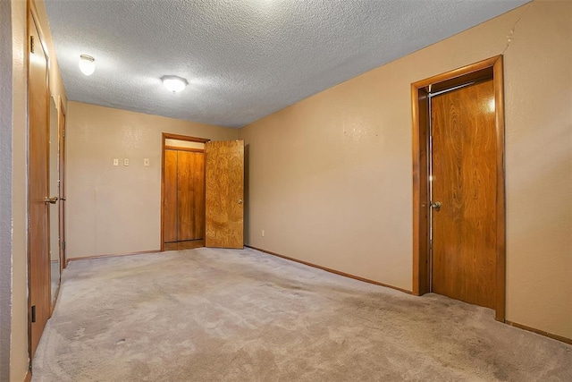 empty room with light colored carpet and a textured ceiling