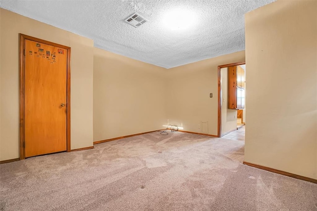 unfurnished room featuring light colored carpet and a textured ceiling