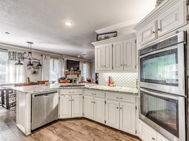 kitchen featuring white cabinets, kitchen peninsula, sink, and appliances with stainless steel finishes