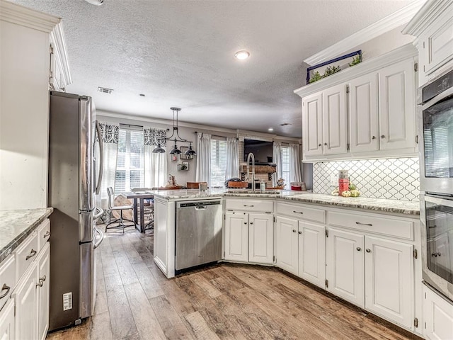 kitchen with white cabinetry, light hardwood / wood-style flooring, kitchen peninsula, decorative light fixtures, and appliances with stainless steel finishes