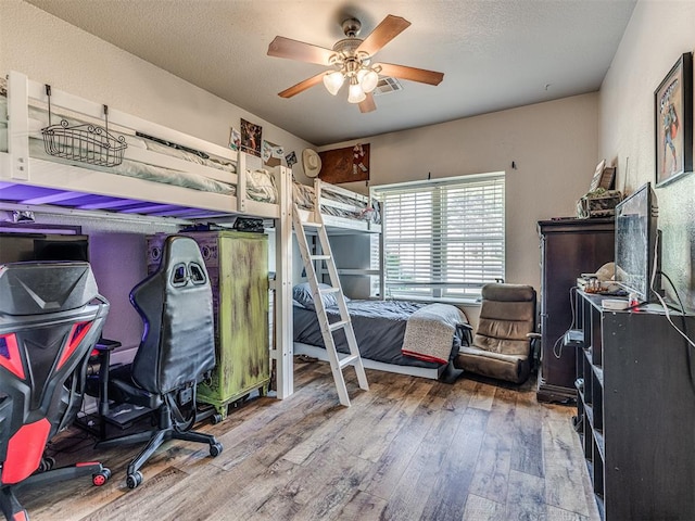 bedroom featuring ceiling fan, wood-type flooring, and a textured ceiling