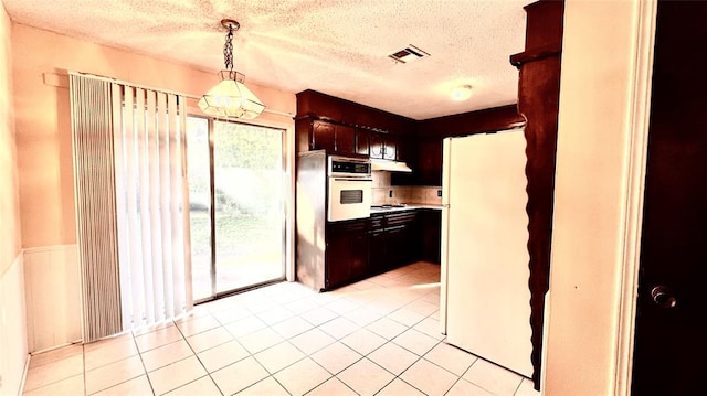 kitchen featuring decorative light fixtures, light tile patterned flooring, white appliances, and a textured ceiling