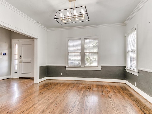 unfurnished dining area with a chandelier, wood-type flooring, and ornamental molding