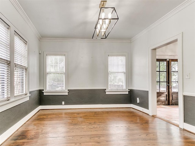 spare room with hardwood / wood-style floors, ornamental molding, and a notable chandelier