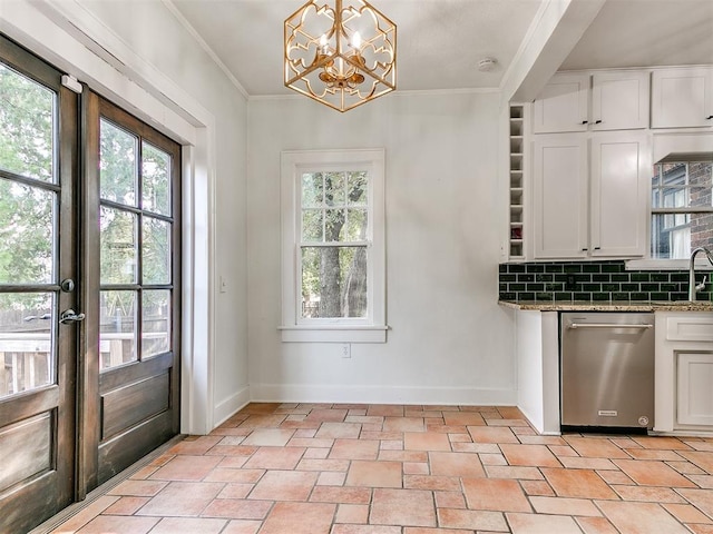 interior space with tasteful backsplash, stainless steel dishwasher, a healthy amount of sunlight, decorative light fixtures, and white cabinetry