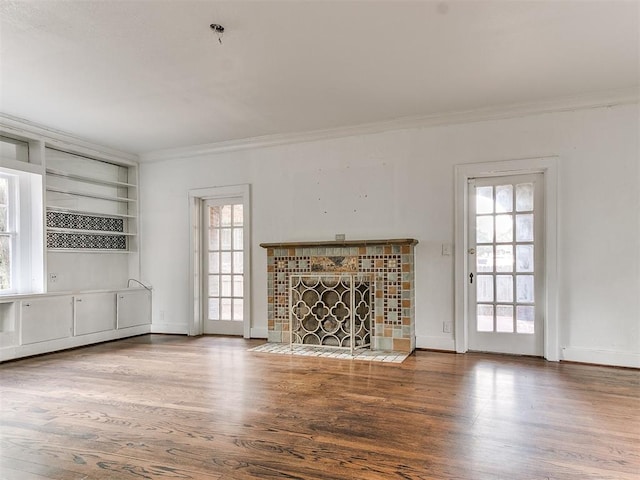 unfurnished living room with a fireplace, wood-type flooring, ornamental molding, and a healthy amount of sunlight