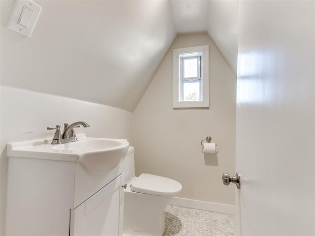 bathroom with toilet, vanity, and vaulted ceiling