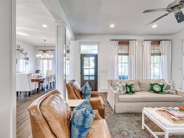 living room with decorative columns, light hardwood / wood-style floors, and ceiling fan with notable chandelier