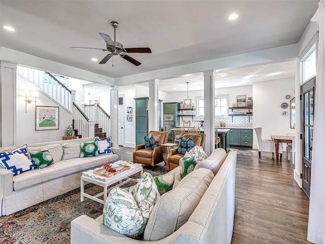 living room with ornate columns, ceiling fan, and dark wood-type flooring