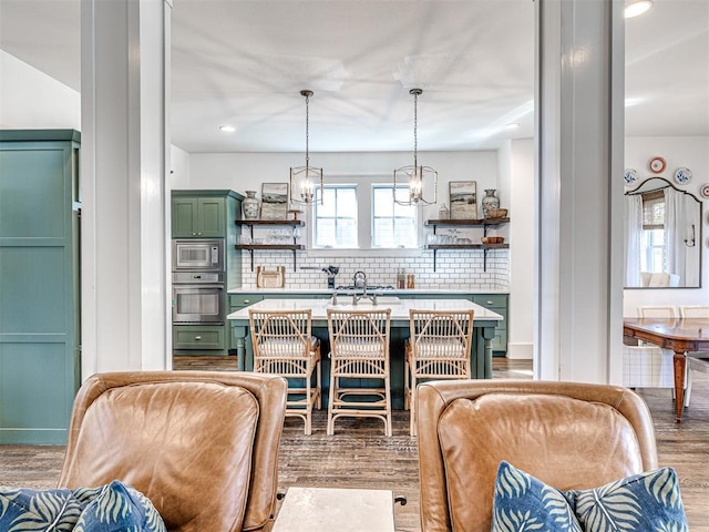 kitchen with decorative backsplash, stainless steel appliances, decorative light fixtures, hardwood / wood-style floors, and green cabinets