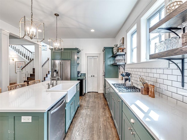 kitchen featuring pendant lighting, a kitchen island with sink, sink, dark hardwood / wood-style floors, and stainless steel appliances