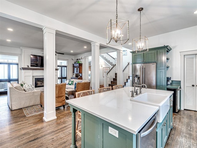 kitchen featuring dark wood-type flooring, decorative light fixtures, an island with sink, appliances with stainless steel finishes, and a notable chandelier