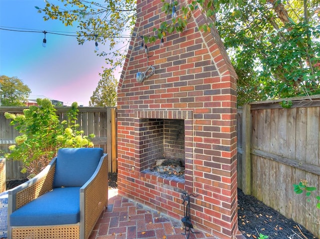 patio terrace at dusk featuring an outdoor brick fireplace