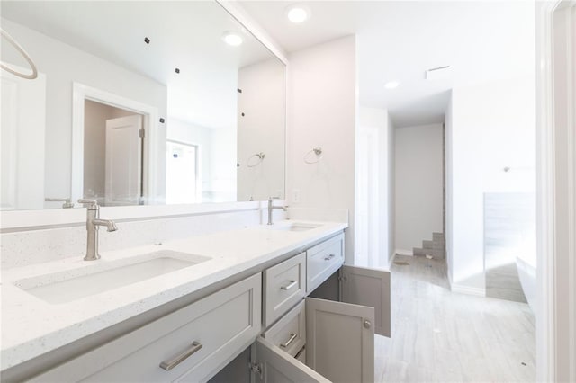 bathroom with double vanity, recessed lighting, baseboards, and a sink