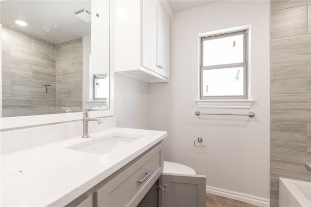 bathroom with vanity, a bathing tub, baseboards, and a tile shower