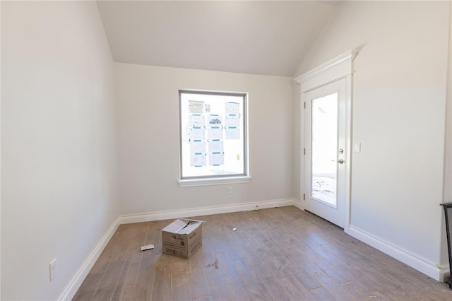 empty room with vaulted ceiling, baseboards, and wood finished floors