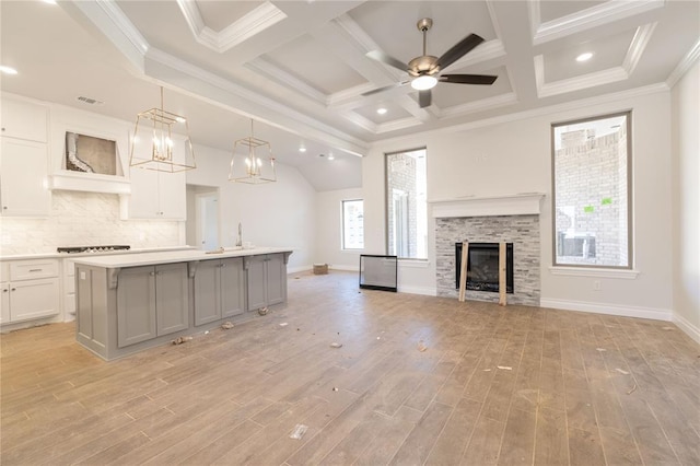 kitchen with light wood-type flooring, gray cabinetry, backsplash, open floor plan, and light countertops