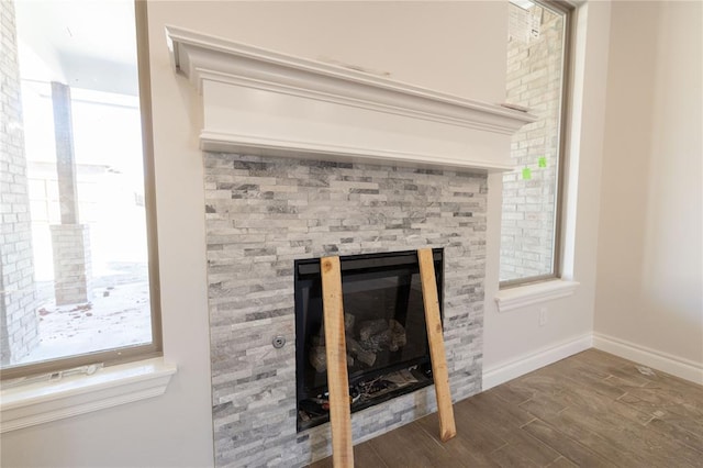 room details with a glass covered fireplace, baseboards, and wood finished floors