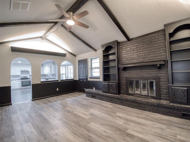 unfurnished living room featuring a fireplace, lofted ceiling with beams, hardwood / wood-style flooring, and ceiling fan