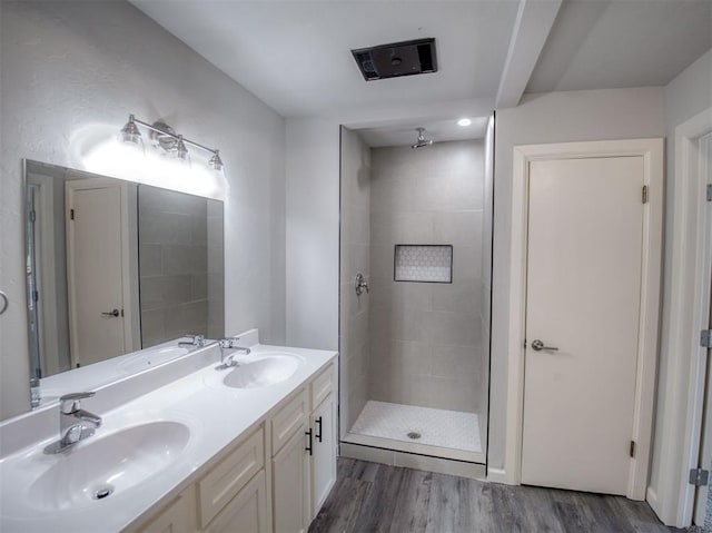 bathroom featuring vanity, wood-type flooring, and tiled shower