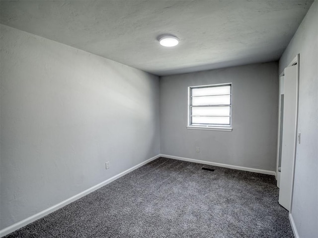 unfurnished room with dark carpet