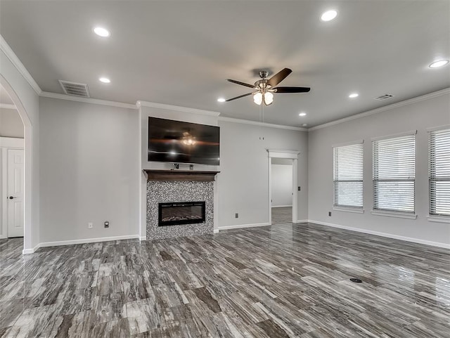 unfurnished living room featuring a fireplace, ceiling fan, wood-type flooring, and crown molding