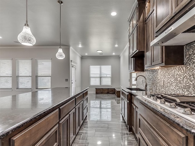 kitchen with ornamental molding, dark brown cabinets, hanging light fixtures, and sink