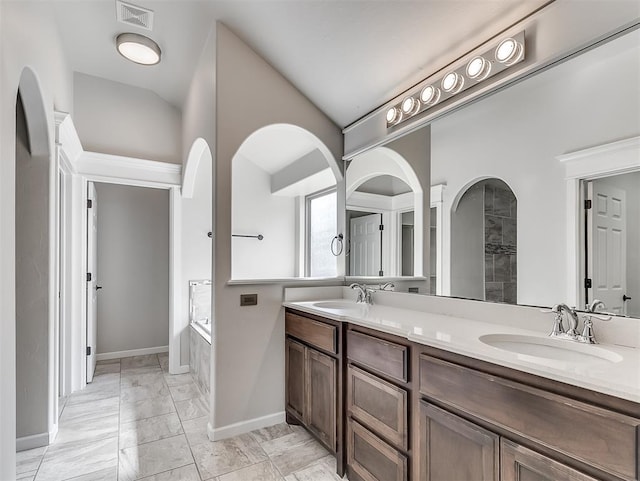 bathroom featuring vanity, a tub to relax in, and vaulted ceiling