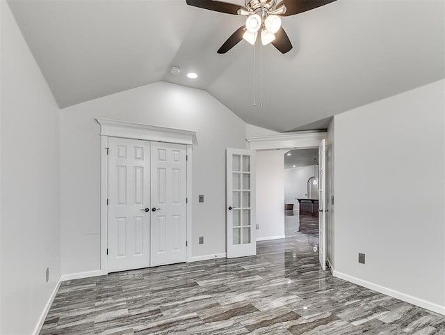 unfurnished bedroom with ceiling fan, a closet, french doors, and vaulted ceiling