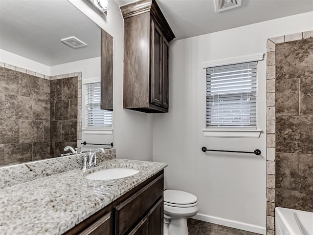 full bathroom with tile patterned floors, tiled shower / bath, vanity, and toilet