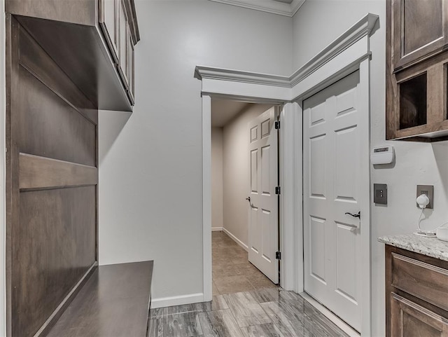 interior space featuring light stone counters, dark brown cabinets, and ornamental molding