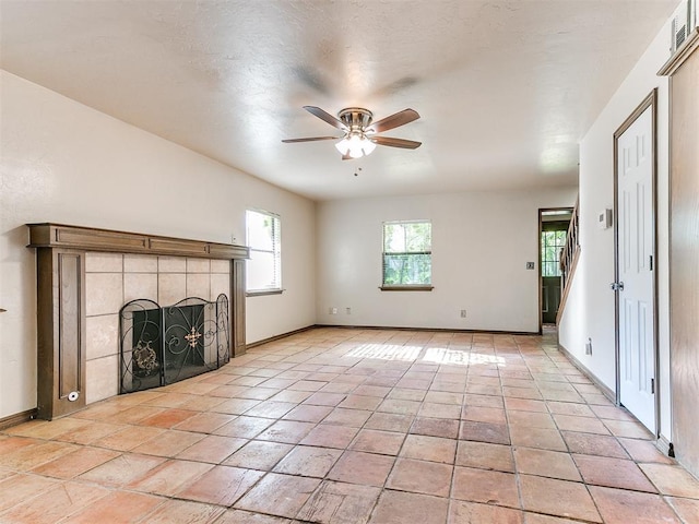 unfurnished living room with a tile fireplace and ceiling fan