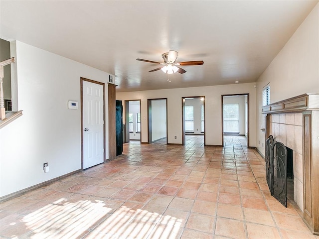 unfurnished living room with ceiling fan, light tile patterned floors, and a fireplace