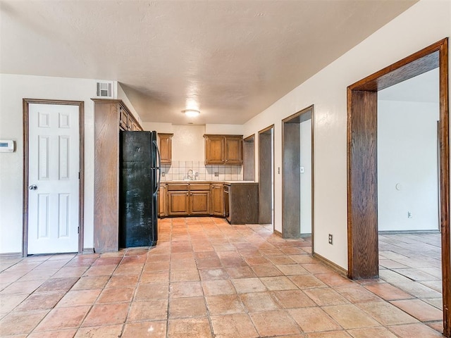 kitchen with black refrigerator, decorative backsplash, and sink