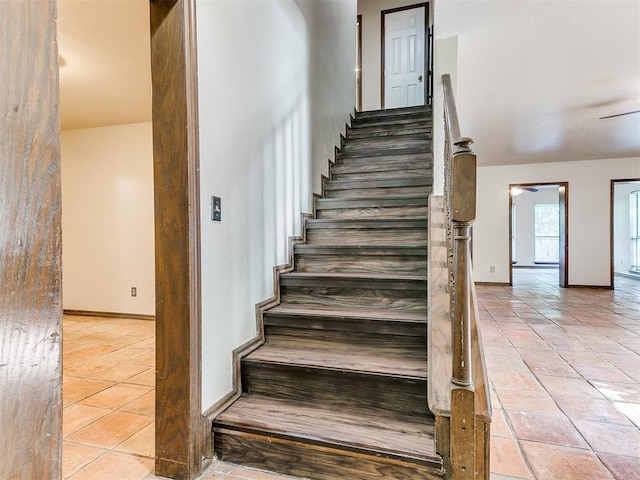 staircase featuring tile patterned flooring and ceiling fan