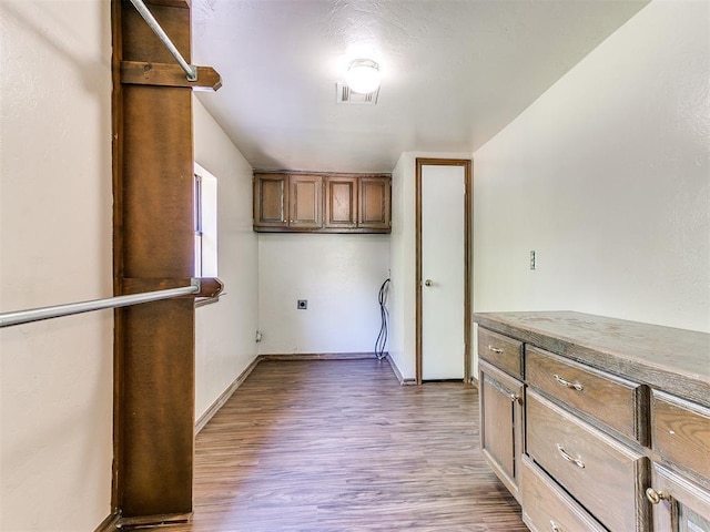 clothes washing area featuring cabinets and light wood-type flooring