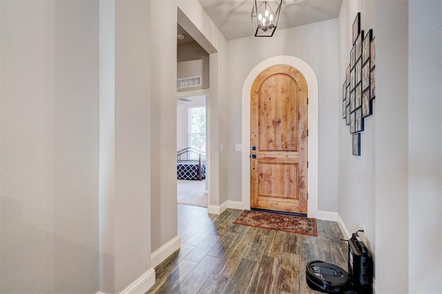 entryway with dark wood-type flooring and a notable chandelier