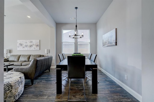 dining space featuring dark wood-type flooring and a chandelier