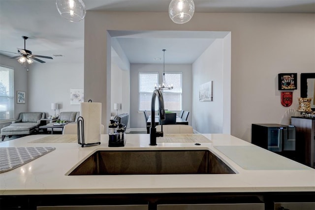 kitchen with plenty of natural light, ceiling fan with notable chandelier, decorative light fixtures, and sink