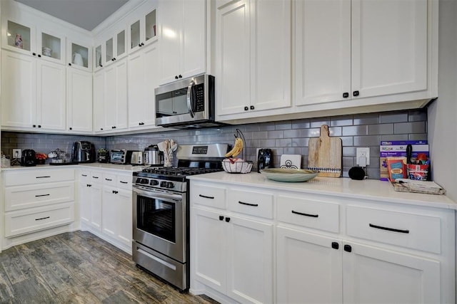 kitchen featuring tasteful backsplash, white cabinetry, dark hardwood / wood-style flooring, and appliances with stainless steel finishes