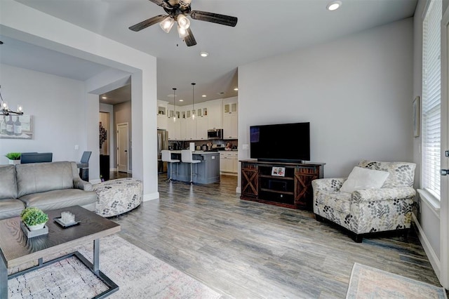 living room with hardwood / wood-style floors and ceiling fan with notable chandelier