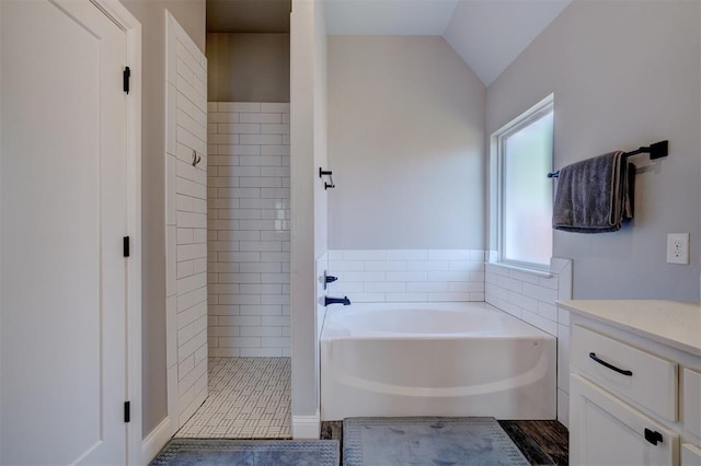 bathroom with tile patterned floors, vanity, separate shower and tub, and vaulted ceiling