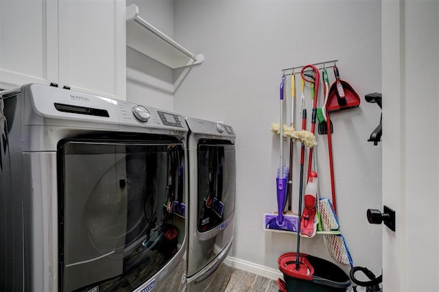 washroom featuring hardwood / wood-style flooring, cabinets, and washing machine and clothes dryer