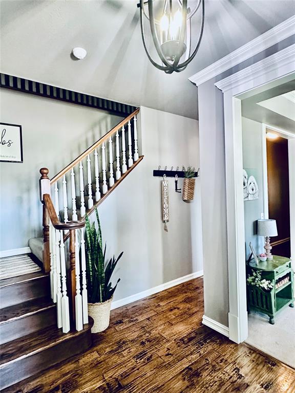 stairs featuring hardwood / wood-style flooring, an inviting chandelier, and ornamental molding